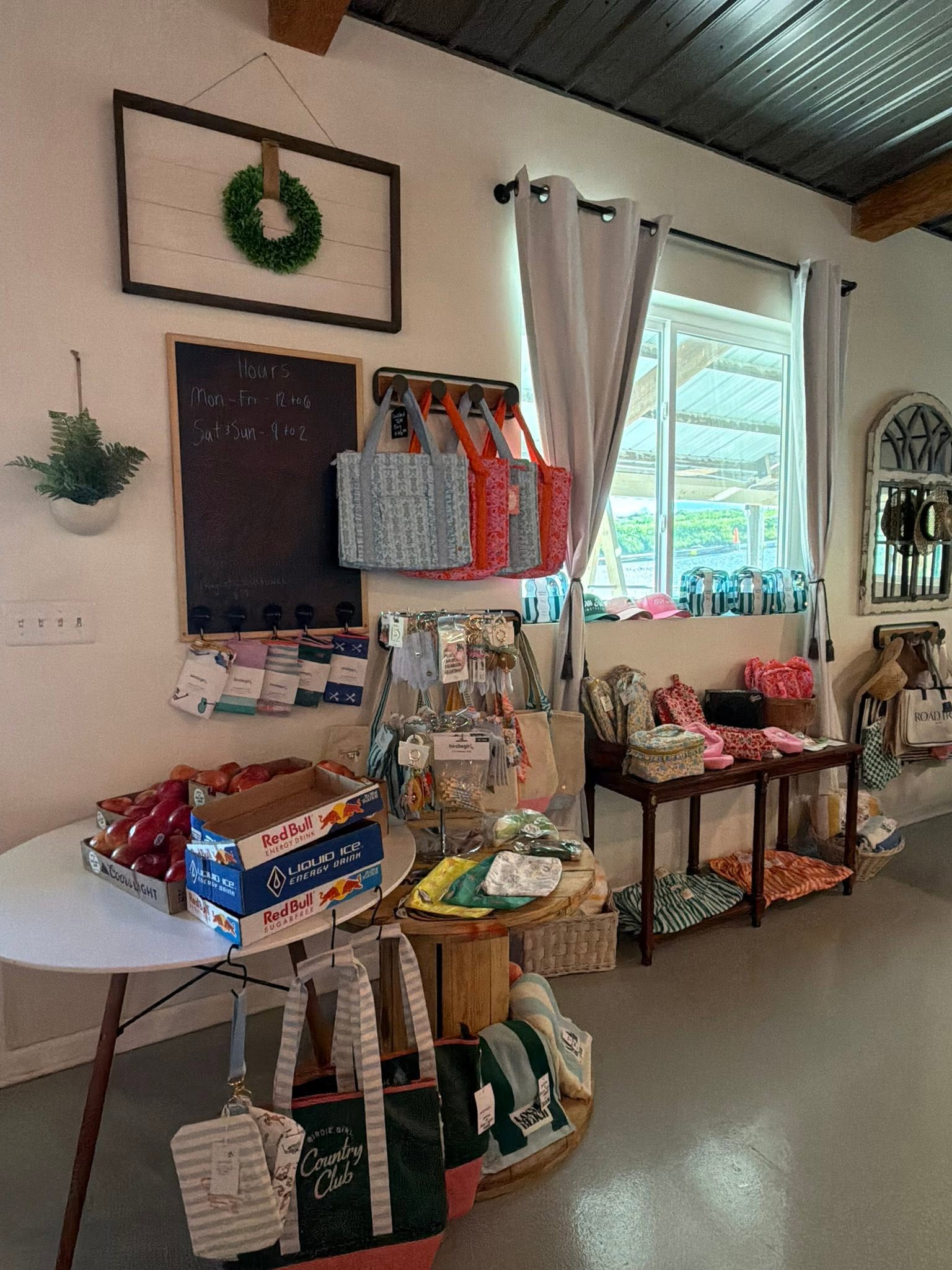 Mercantile shopping area with tote bags, produce, and the hours chalkboard